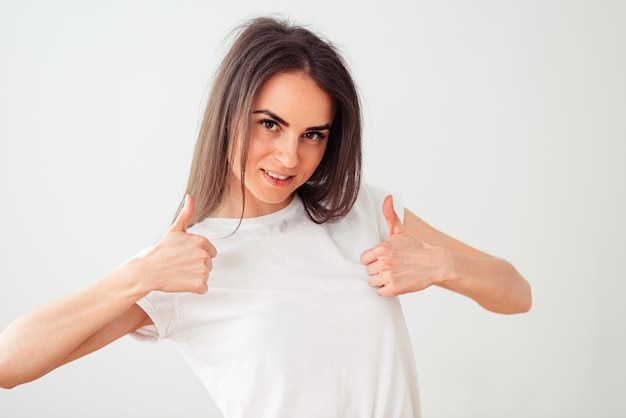 European woman shows thumb up with both hands and smiles sweetly. girl on a light background