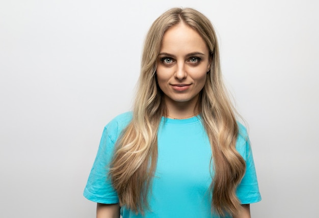 European young woman in a blue tank top on a white background with free space