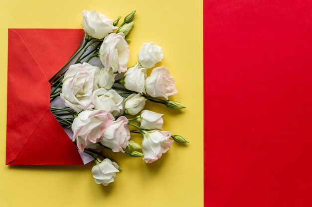 Eustoma flowers with envelope on colorful background.Opened envelope with white flowers arrangements.Festive greeting concept.bright fresh composition