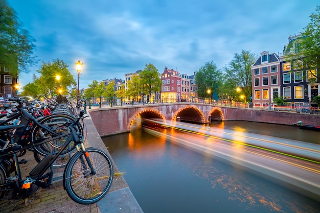 Evening in Amsterdam Panoramic views of the famous old houses bicycles bridge and canal in the old center Long exposure Amsterdam Holland Netherlands Europe