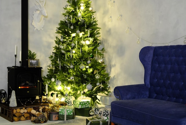 Evening Christmas atmosphere The Christmas tree is illuminated by a garland next to it is a sofa and an artificial fireplace