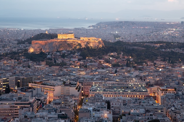 Evening cityscape of Athens, Greece featuring Acropolis with brightly lit ancient Greek Parthenon