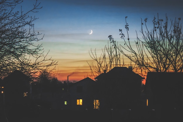 Photo evening house in the shade and the young month.