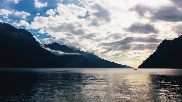 Evening landscape of mountain lake with cloudy skyand dark mountains silhouettes