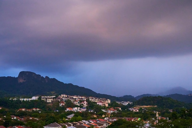 Evening rainy cloud bring rain to city under green hill