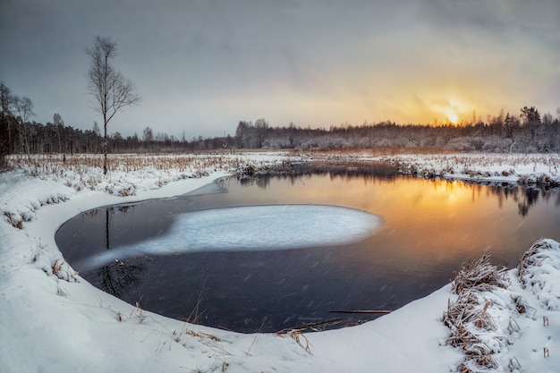 Evening winter sunny sunset landscape with backwater and ice on the river.