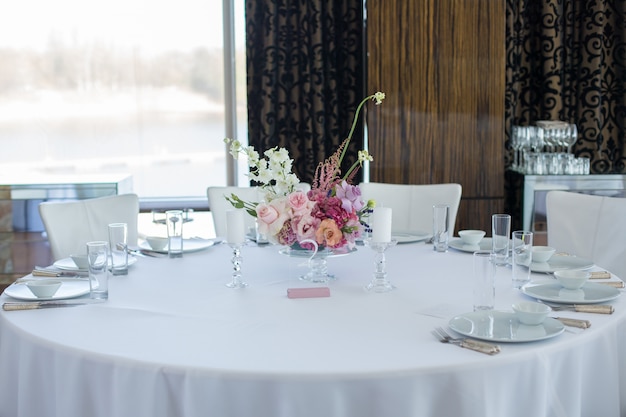 Event white restaurant table served and decorated with delicate fresh flowers