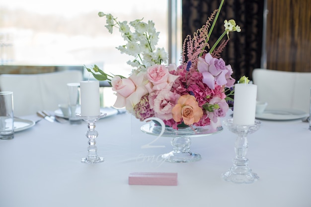 Event white restaurant table served and decorated with delicate fresh flowers.