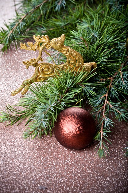 Evergreen fir tree branch, golden deer, brown ball.