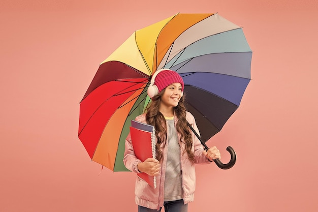 Every day fun Child enjoying simple things Entertain yourself Fun concept Feeling good Girl having fun walking wireless headphones under colorful umbrella Fall leisure Music always with me