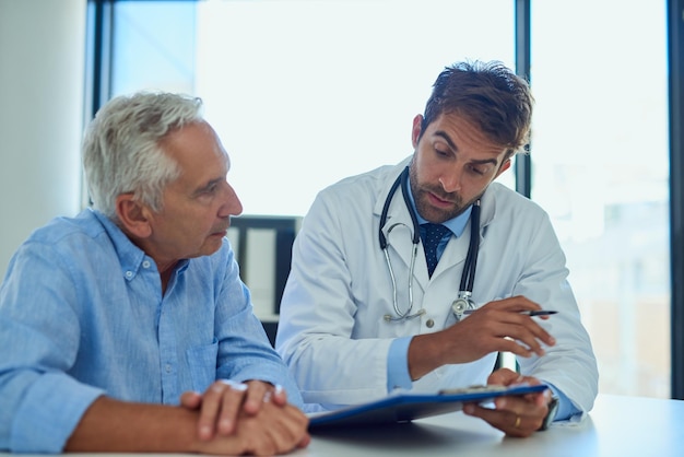 Every patient should have a clear understanding of their diagnostic Shot of a handsome doctor going over some paperwork with a male senior patient in a clinic