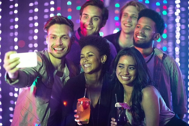 Everybody say cheese Shot of a happy group of friends taking a selfie with a smartphone in a nightclub