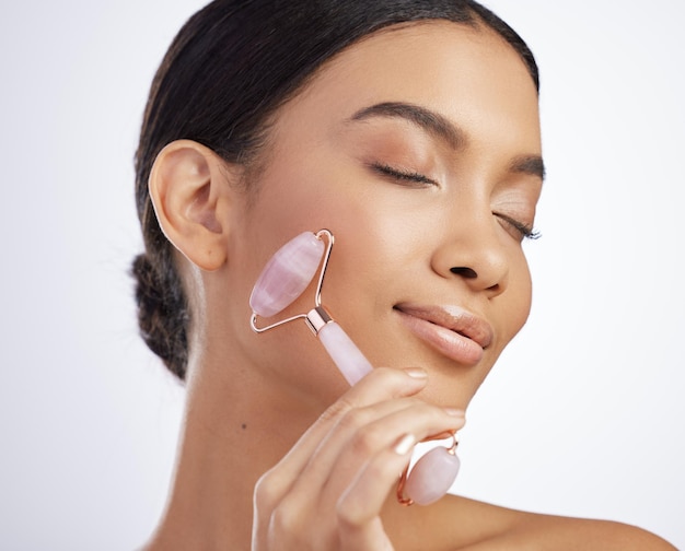 Everyday should feel like a spa day Studio shot of an attractive young woman using a jade roller on her face against a grey background