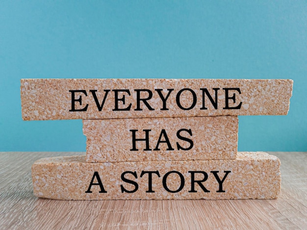 Everyone Has a Story message written on brick blocks Beautiful blue background wooden table