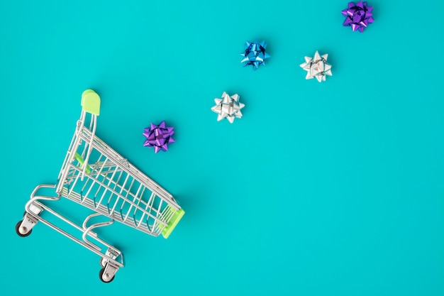 Everything for the holiday and gift wrapping bows fly into the cart trolley on a green background with copy space