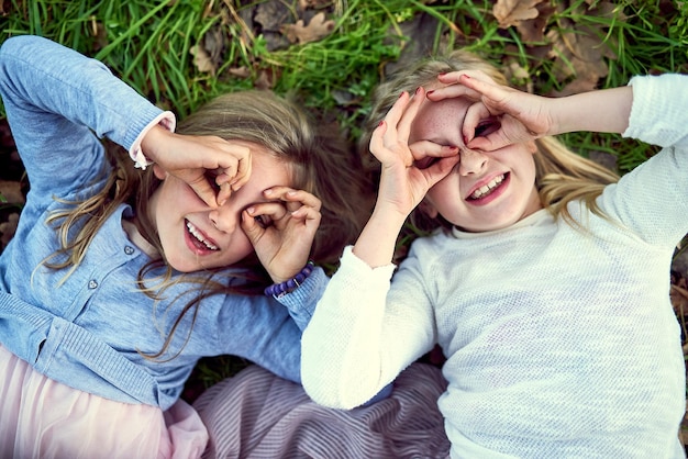 Photo everything is fun when youre young portrait of two little sisters lying on the grass outside