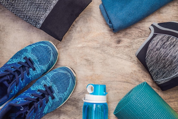 Everything for sports turquoise blue shades on a wooden background Yoga mat sport shoes sportswear and bottle of water Concept healthy lifestyle sport and diet Sport equipment Copy space