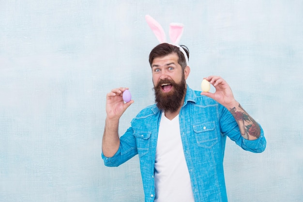 Everything you need for Easter is here Hipster long ears holding egg Culture customs and traditions Easter bunny colored eggs Celebration of spring holiday Bearded man bunny ears and Easter eggs