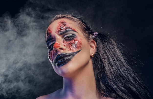 Evil psycho clown makeup looks especially creepy in a smoke over dark background.