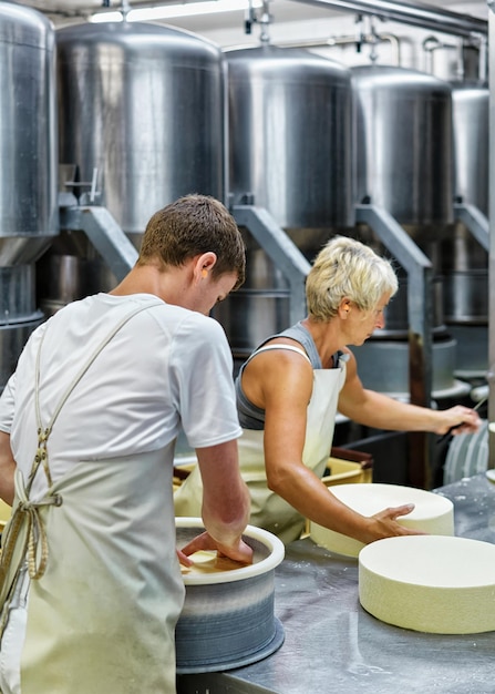 Evillers, France - August 31, 2016: Cheese-makers putting young Gruyere de Comte Cheese in the forms at the dairy in Franche Comte, Burgundy, in France.