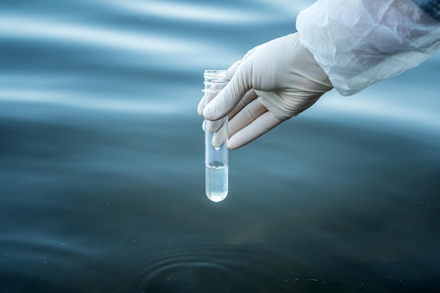 Photo examination of water quality in natural reservoir test tube in a mans hand with water to check its purity