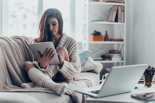 Examining her new tablet. Beautiful young woman in casual wear looking at her digital tablet 