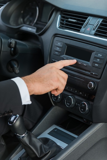 Examining his new car. Close-up of man in formalwear touching dashboard with finger while sitting in car