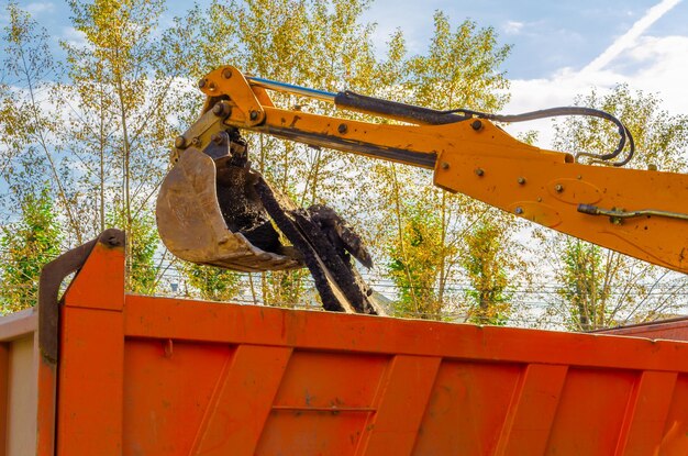 Excavator bucket over the dump truck body.
