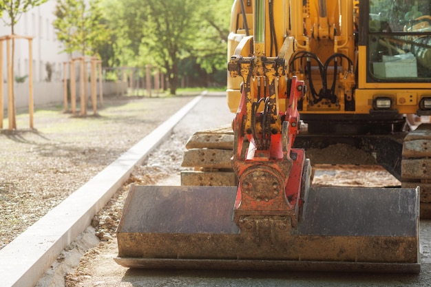 Excavator Constructs New Sidewalk Footpath in park Excavator works with wide bucket Road works