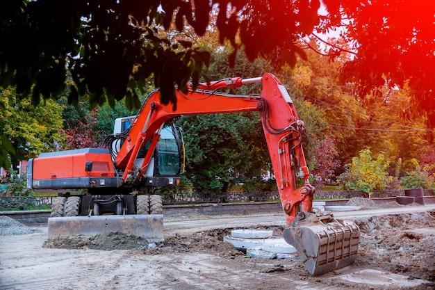 Excavator digging hole, breaking street asphalt, repairing damaged water supply pipe