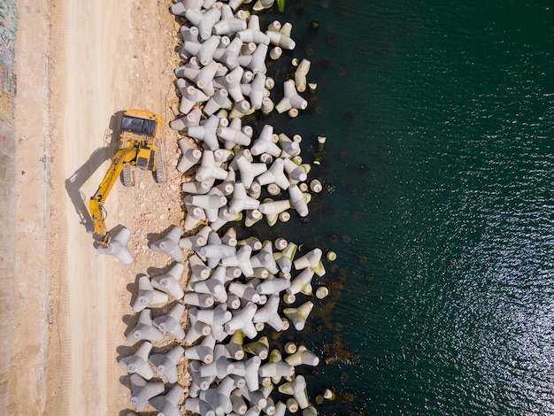 Photo an excavator diligently constructs a dock or breakwater in the sea its mighty arm reaching out from the shore creating a resilient structure amidst the waves aerial view