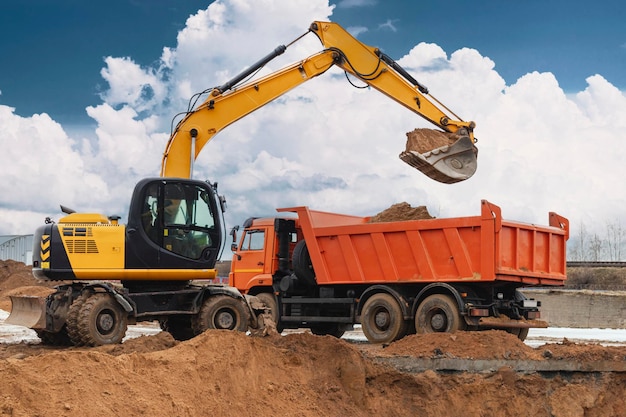 An excavator loads soil or sand into a dump truck Pit development Earthworks with the help of heavy construction equipment