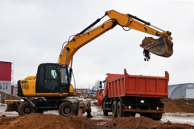 An excavator loads soil or sand into a dump truck Pit development Earthworks with the help of heavy construction equipment