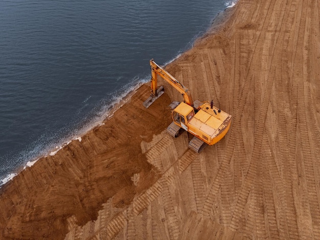 Excavator machine doing an earthwork on a shoreAerial photography