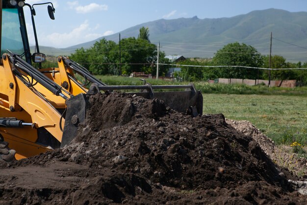 Excavator and new building in the field. build a house