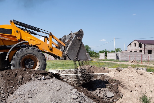 Excavator and new building in the field. build a house