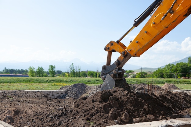 Excavator and new building in the field. build a house