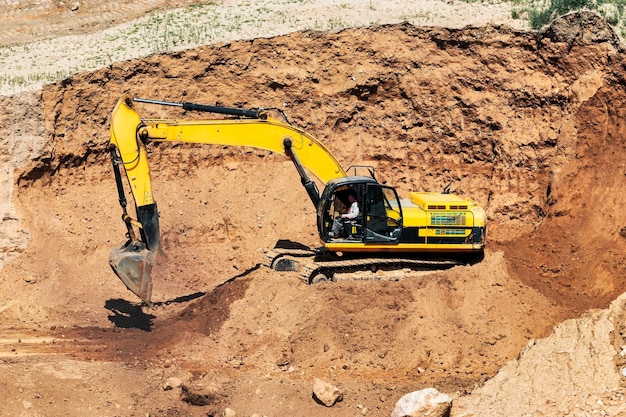 An excavator in a sand pit loads a dump truck with sand Extraction of sand in an open pit natural building materials