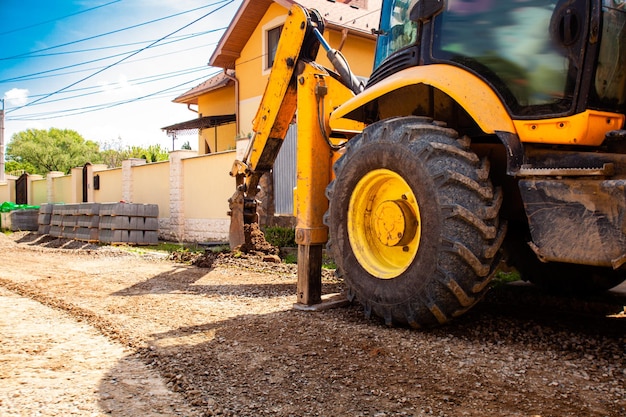 The excavator works on the street before laying paving stones