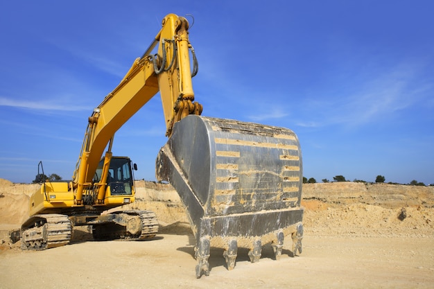 excavator yellow vehicle sand quarry outdoor blue sky