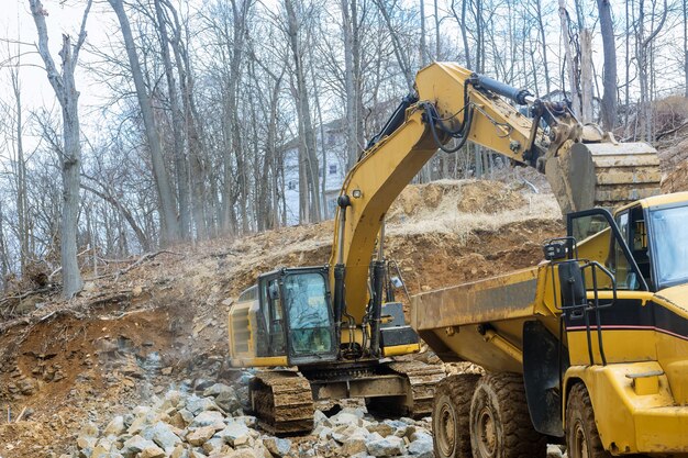 Excavators work with a stone tractor loads trucks stone transports with stone, transporting