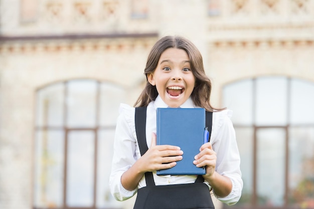 Excited about studying. School education concept. Cute smiling child hold book. Little girl school student. Knowledge day. Learning language. Hooked on learning. School life. Child development.