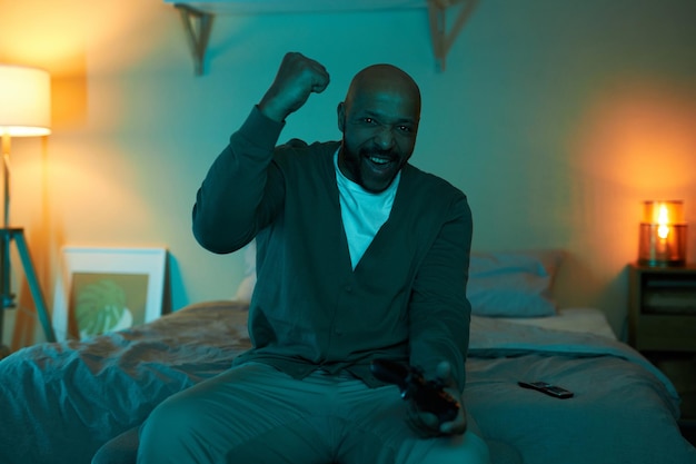 Excited adult black man playing video games in dark and celebrating victory