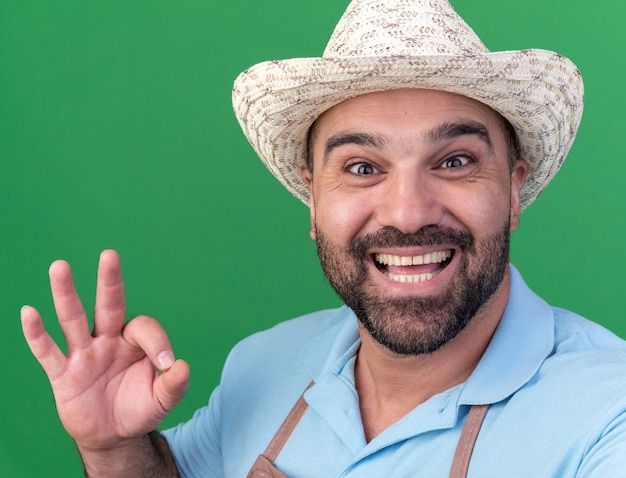 Excited adult caucasian male gardener wearing gardening hat gesturing ok sign looking at camera 