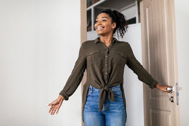 Excited African American Lady Entering Home Standing In Opened Door