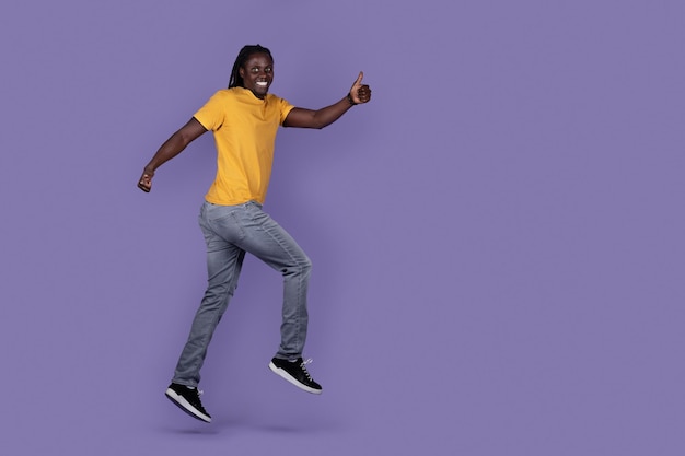 Excited african guy running in the air showing thumb up