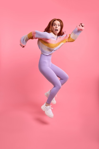 Excited amazed female jump run after sales discounts scream wow omg expression, caucasian lady hurry, wearing casual outfit isolated over pink studio background