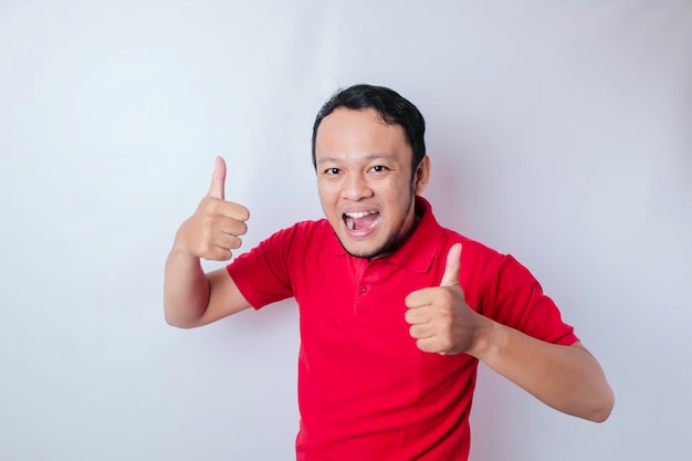 Excited Asian man gives thumbs up hand gesture of approval isolated by white background