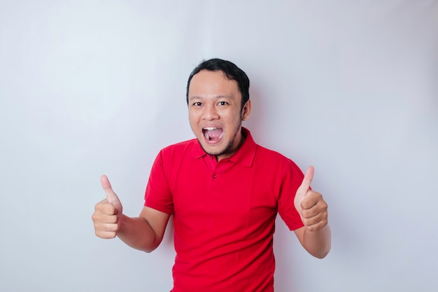 Excited Asian man gives thumbs up hand gesture of approval isolated by white background