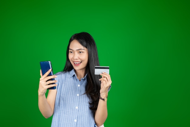 Excited asian woman while using a mobile phone hold credit card